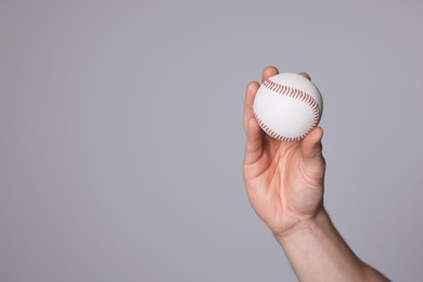 Photo of Man with baseball ball on light grey background, closeup. Space for text