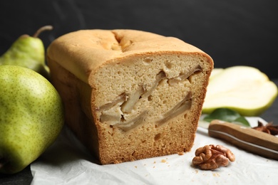 Photo of Tasty cut pear bread on parchment, closeup. Homemade cake