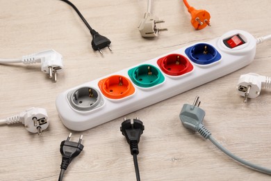 Photo of Power strip with extension cord on white wooden floor. Electrician's equipment