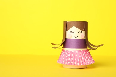 Photo of Toy doll made of toilet paper hub on yellow background. Space for text