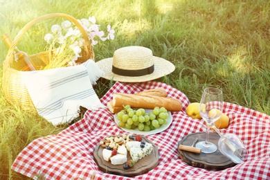 Photo of Picnic blanket with delicious food and wine on green grass in park