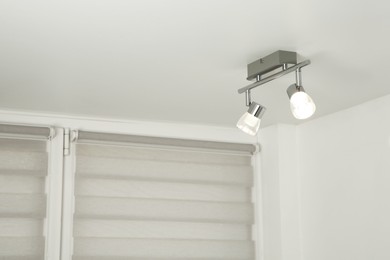 Stylish light fixture on ceiling indoors, low angle view