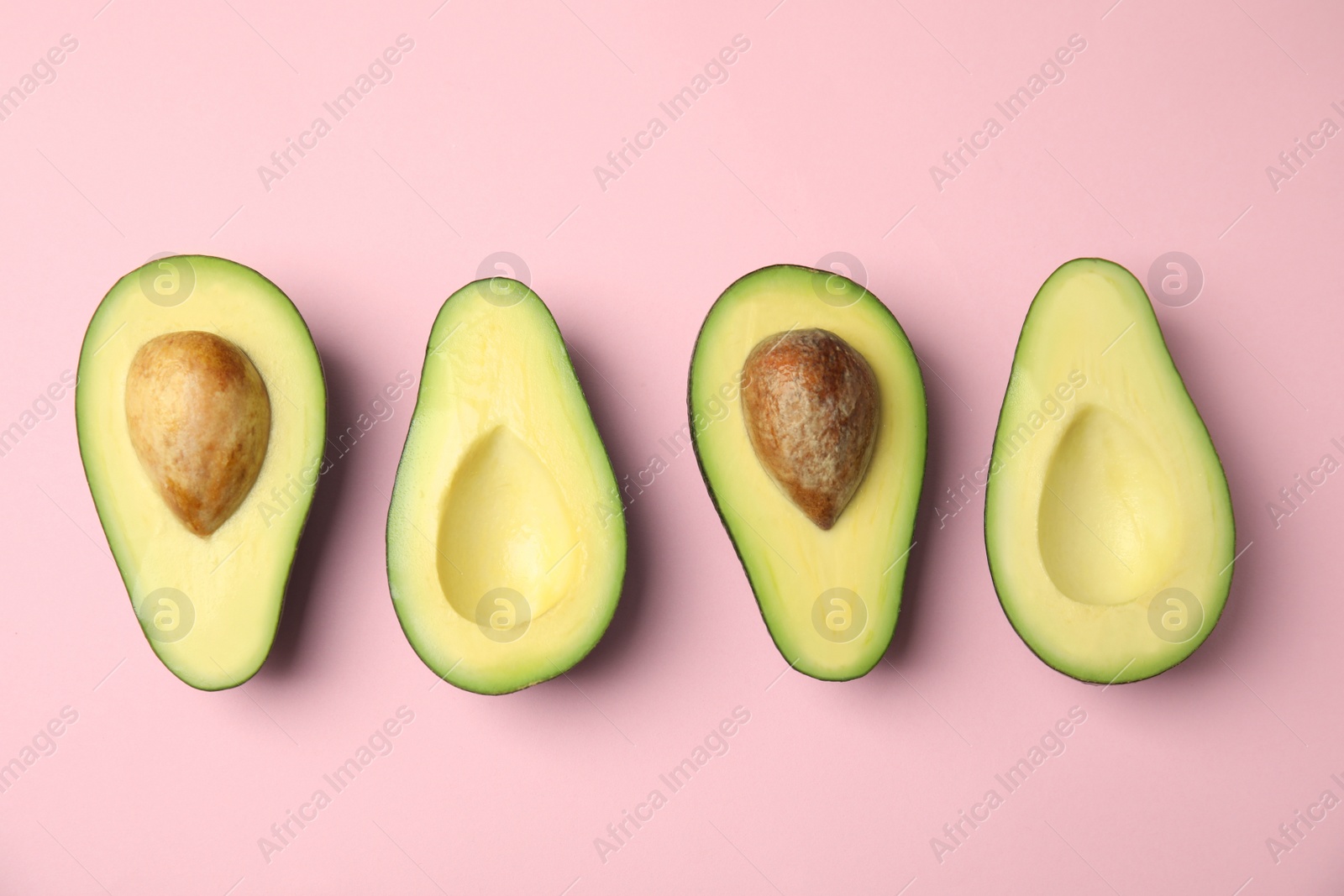 Photo of Cut fresh ripe avocados on pink background, flat lay