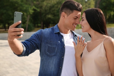 Photo of Lovely couple taking selfie after they got engaged outdoors