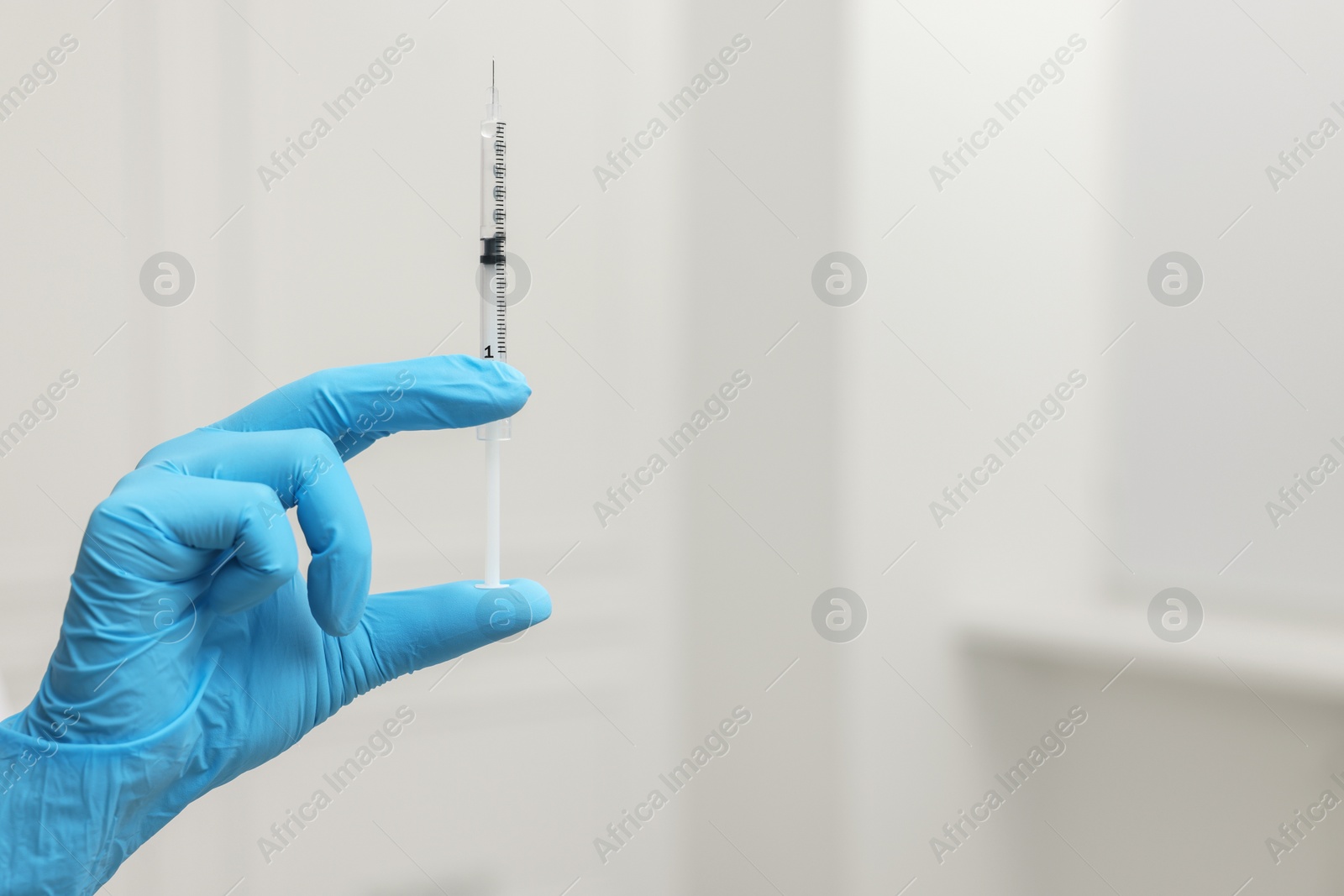 Photo of Doctor holding syringe indoors, closeup. Space for text