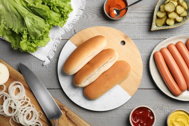 Photo of Different tasty ingredients for hot dog on light grey wooden table, flat lay