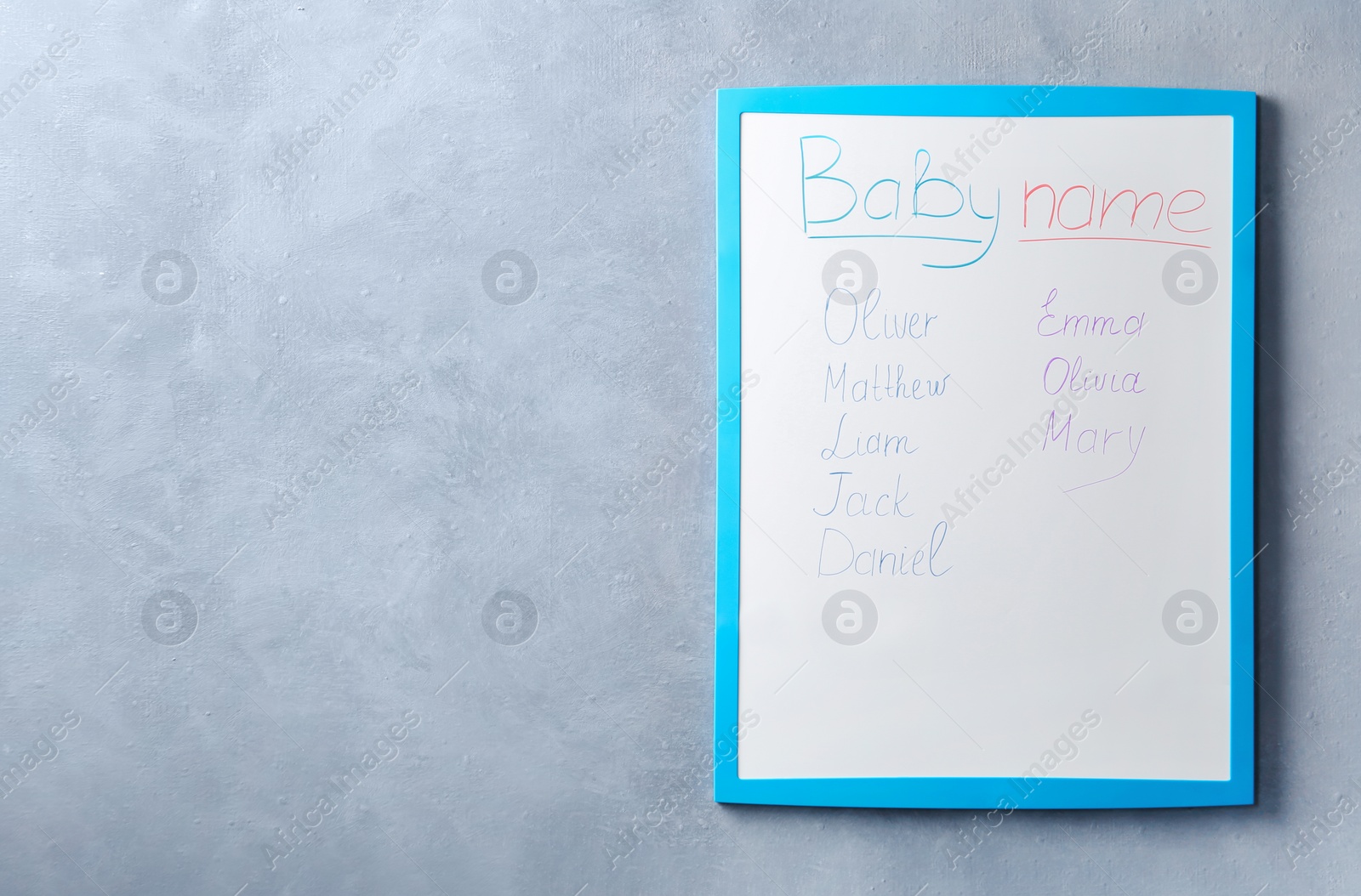 Photo of White board with baby names on grey wall. Space for text