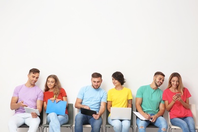 Photo of Group of young people waiting for job interview near light wall