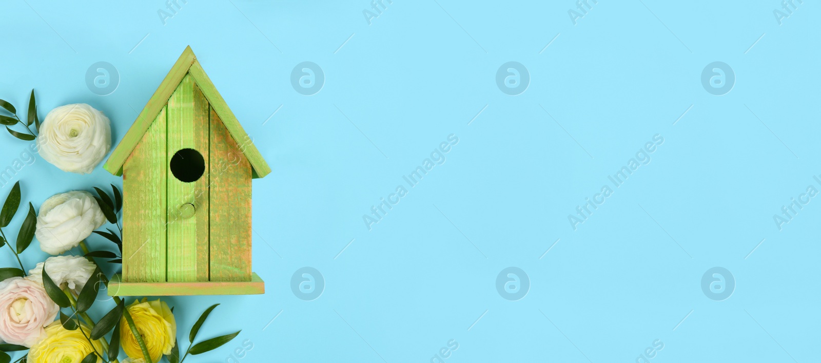 Photo of Stylish bird house and fresh eustoma flowers on light blue background, flat lay. Space for text