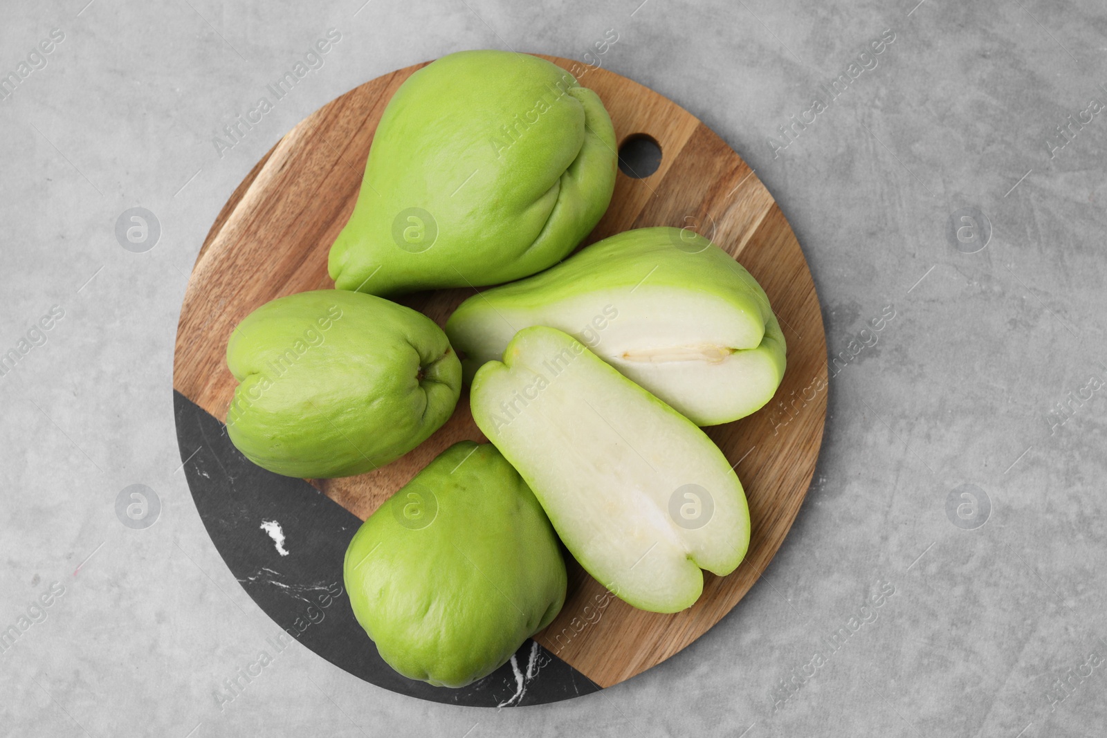 Photo of Cut and whole chayote on gray table, top view