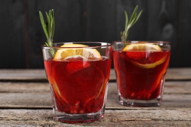 Glasses of delicious refreshing sangria on old wooden table, closeup