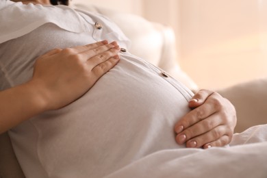 Photo of Pregnant young woman touching belly at home, closeup