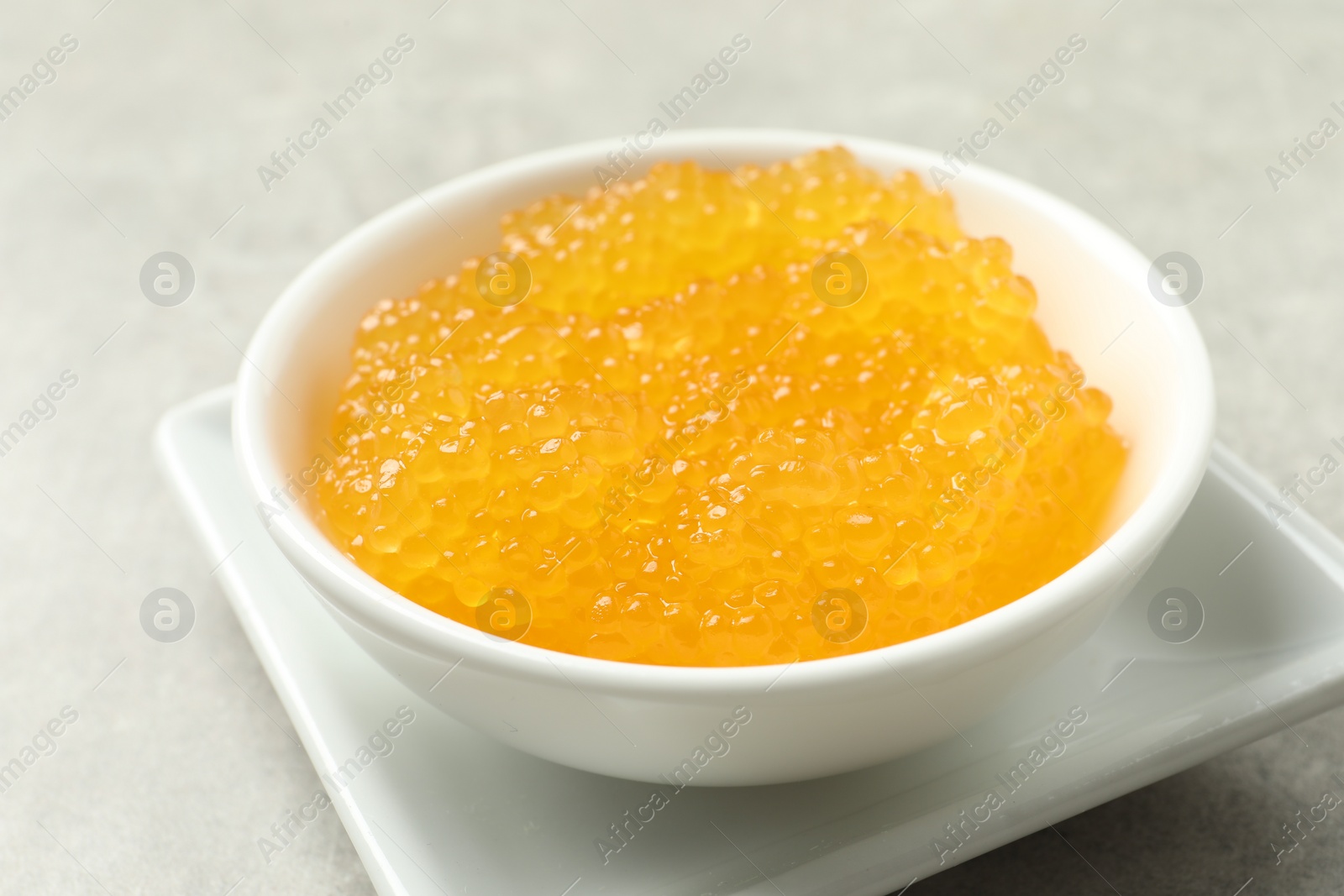 Photo of Fresh pike caviar in bowl on light grey table, closeup