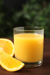 Photo of Glass of orange juice and fresh fruits on wooden table, closeup