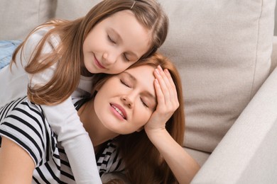 Photo of Mother with her cute daughter spending time together on sofa at home