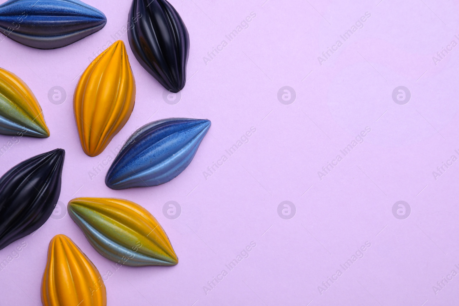 Photo of Tasty chocolate candies on violet background, flat lay. Space for text