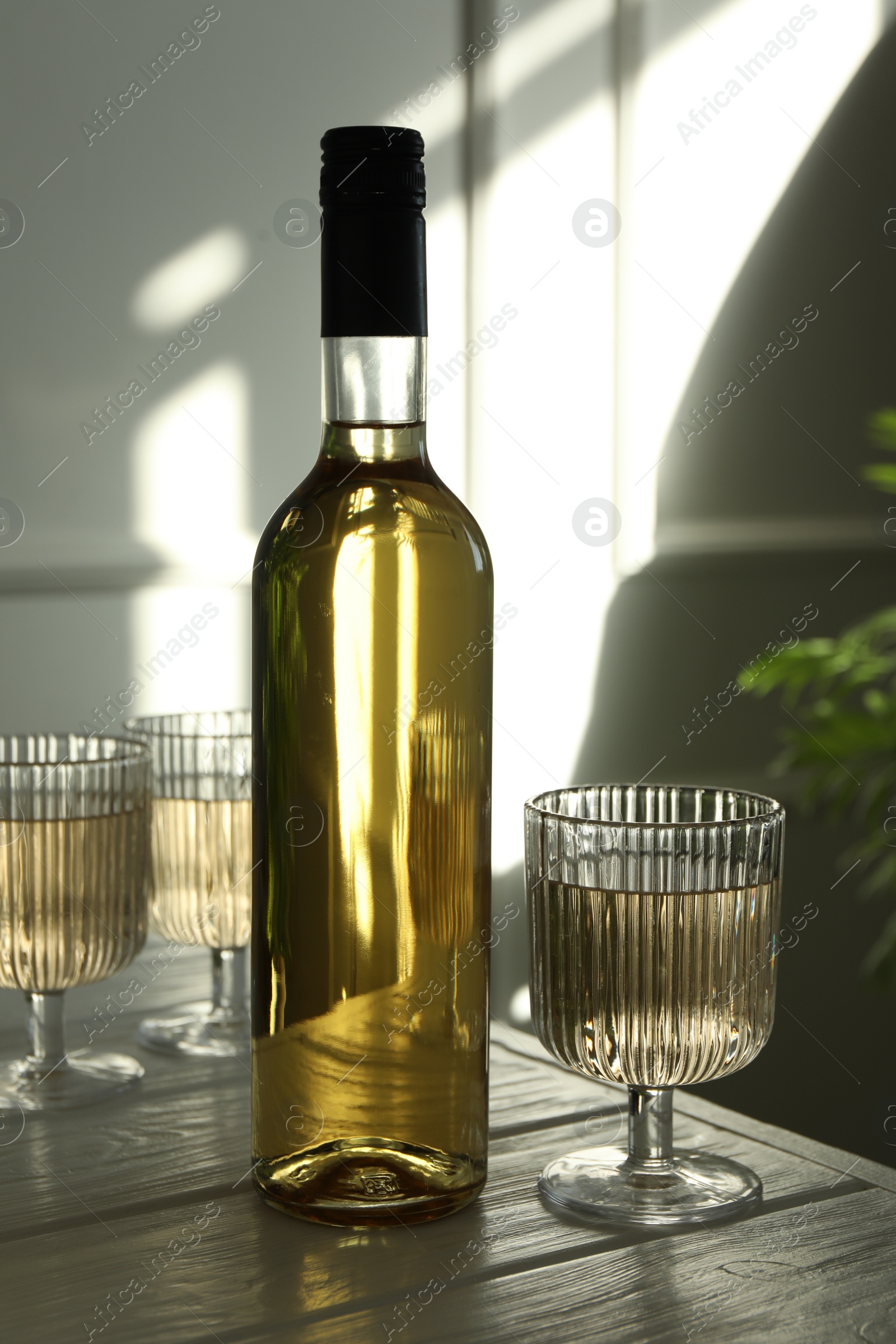 Photo of Alcohol drink in glasses and bottle on wooden table indoors