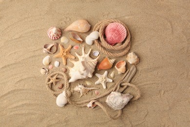 Beautiful sea stars, shells and ropes on sand, flat lay