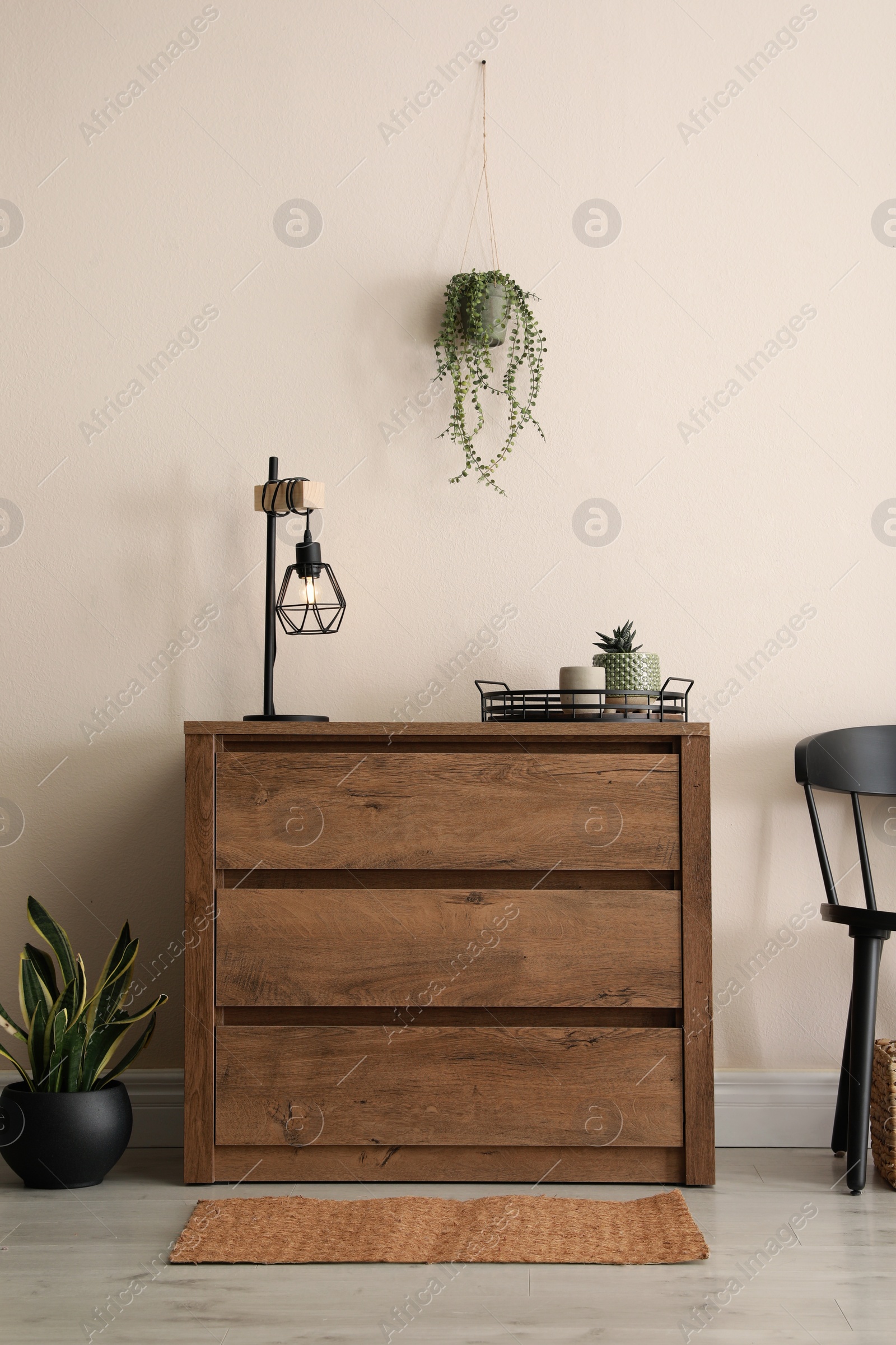 Photo of Room interior with wooden chest of drawers near beige wall