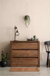 Room interior with wooden chest of drawers near beige wall