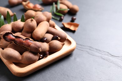 Photo of Wooden plate with delicious ripe tamarinds on black table. Space for text