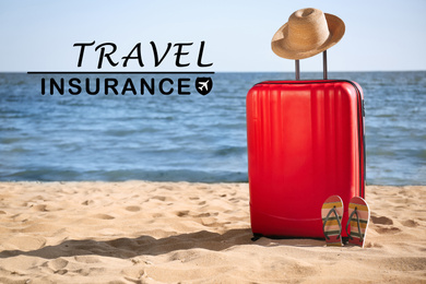 Image of red suitcase, hat and flip flops on sand near sea. Travel insurance