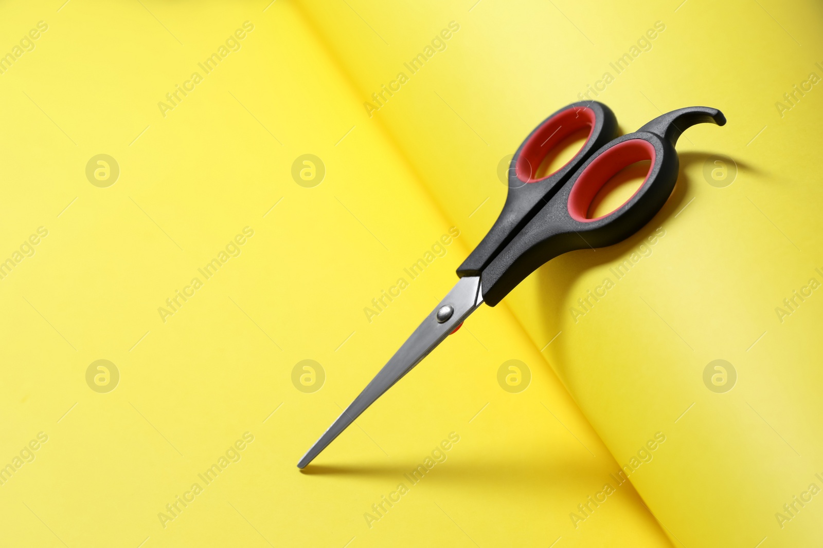 Photo of Scissors and color paper on yellow background. Space for text