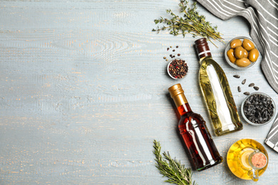 Photo of Flat lay composition with different sorts of cooking oil on grey wooden table. Space for text