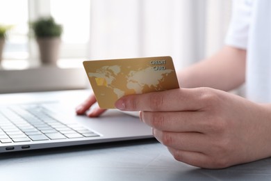 Photo of Online payment. Woman with laptop and credit card at white table, closeup