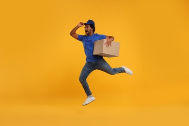 Photo of Happy courier running to deliver parcel on orange background