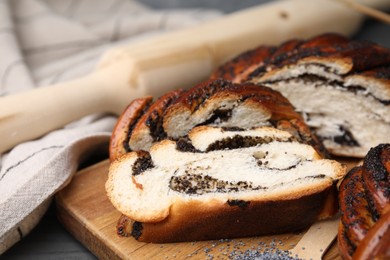 Photo of Pieces of poppy seed roll on table, closeup. Tasty cake