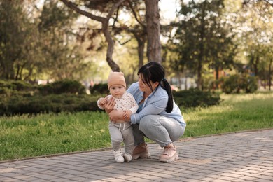 Mother teaching her baby how to walk outdoors