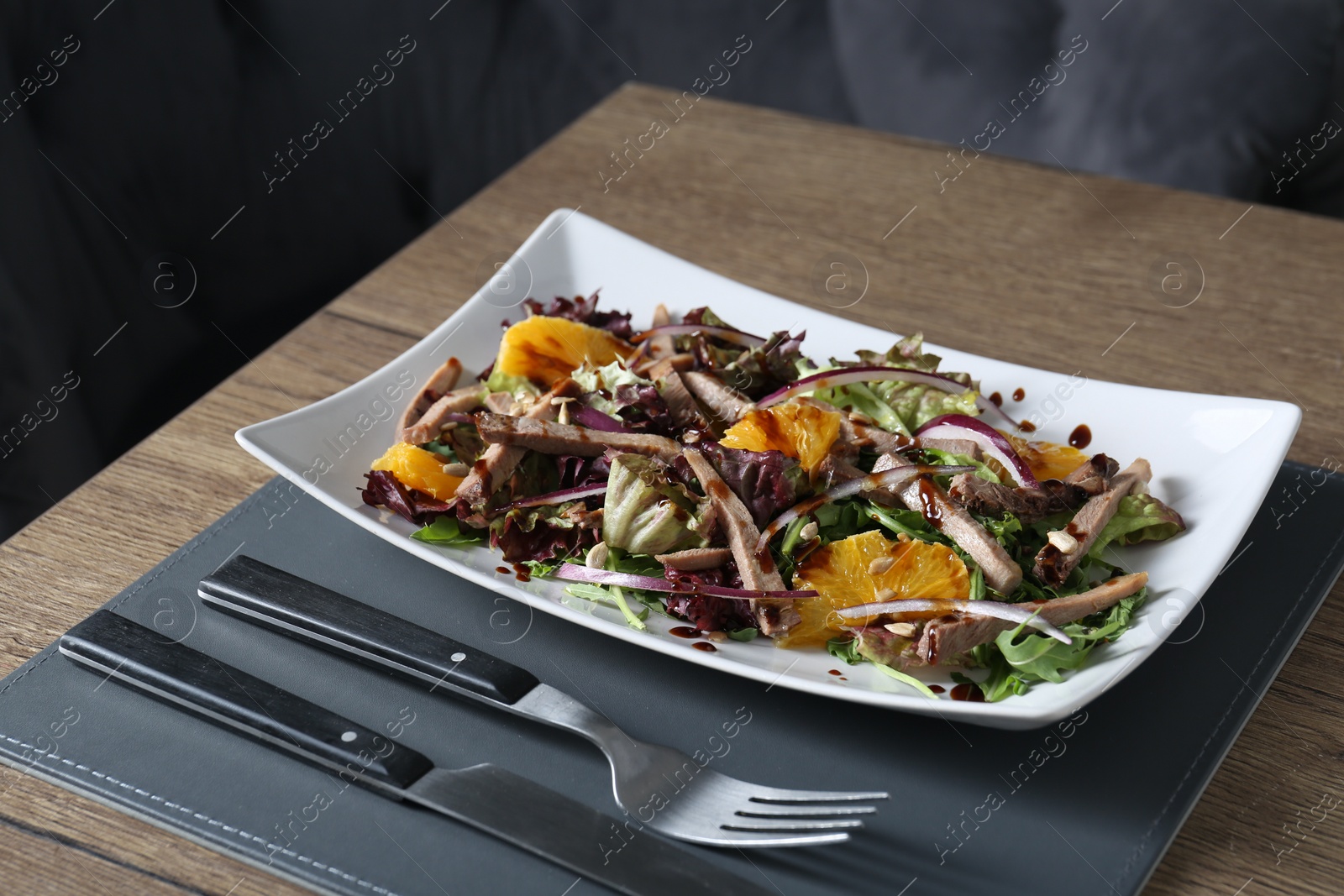 Photo of Delicious salad with beef tongue, orange and onion served on wooden table