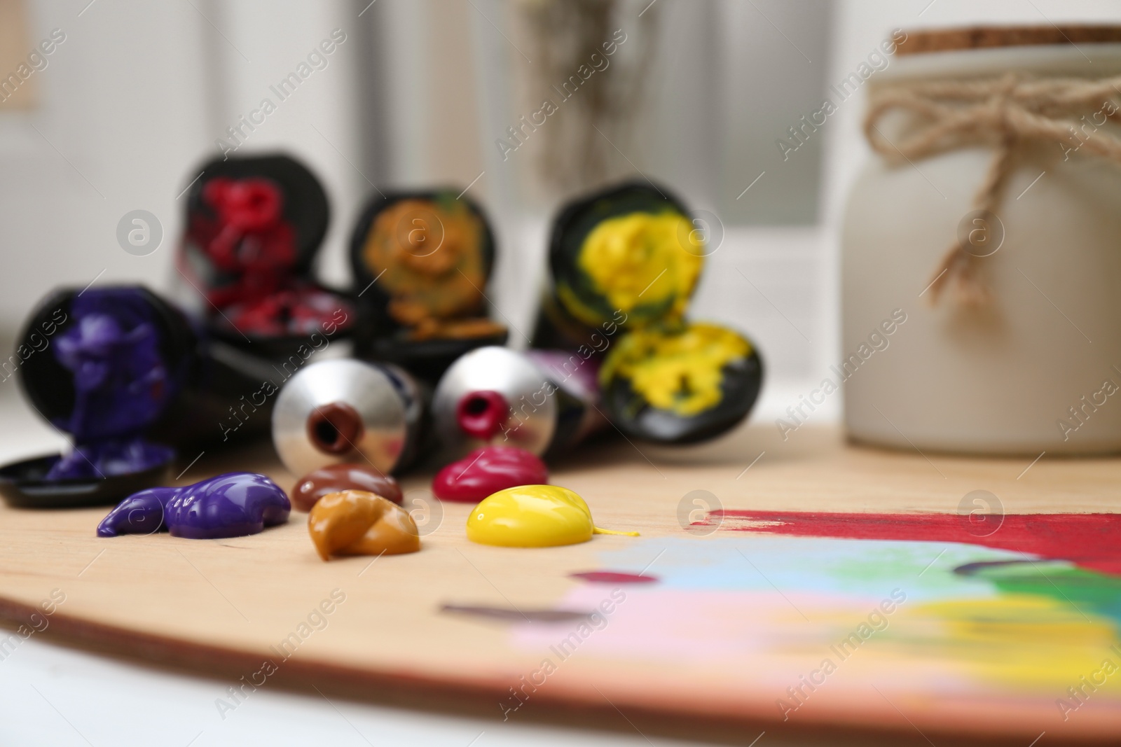 Photo of Wooden artist's palette and colorful paints on table, closeup. Space for text