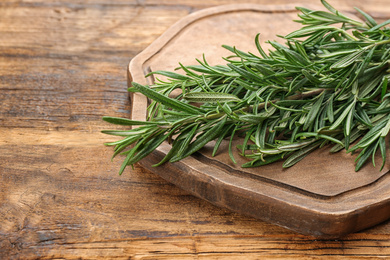 Photo of Bunch of fresh rosemary on wooden table, closeup