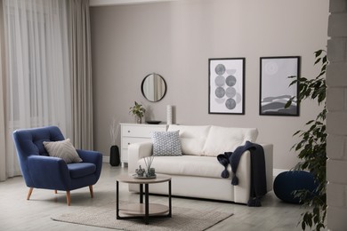 Photo of Stylish living room interior with white sofa, armchair and small coffee table