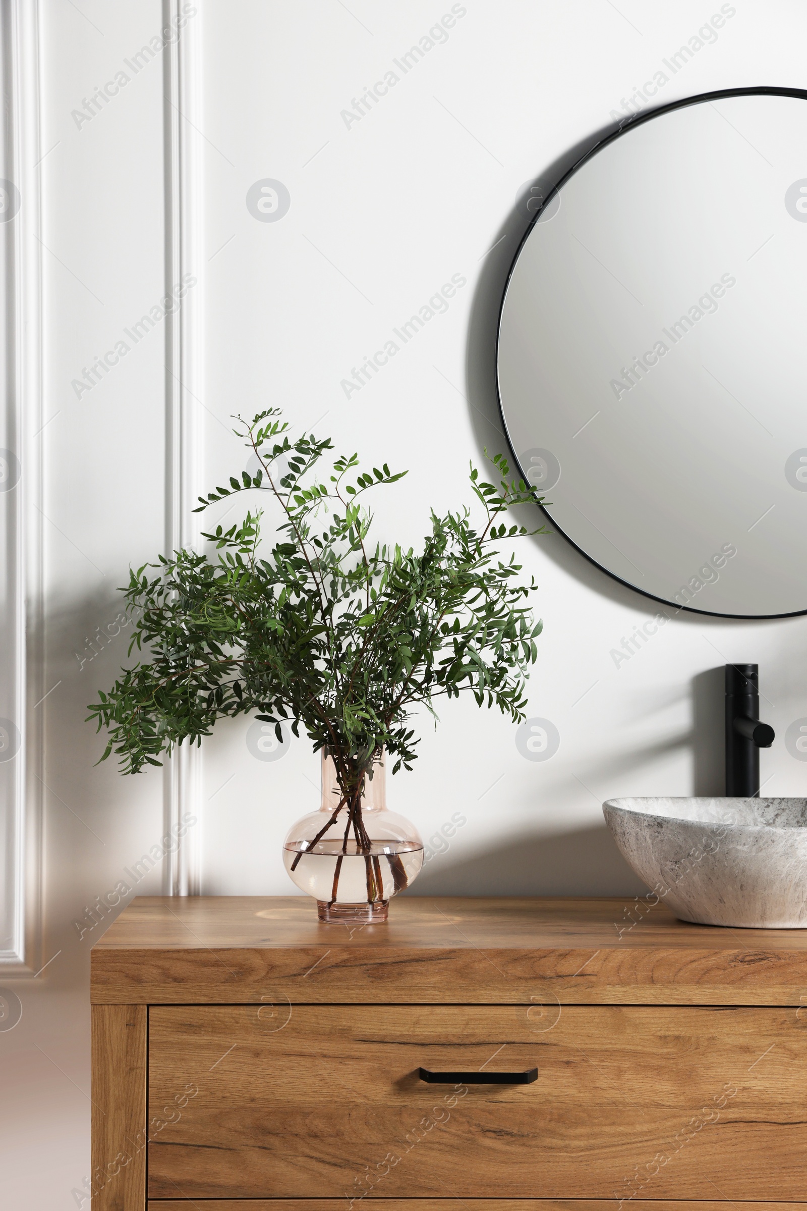 Photo of Modern bathroom interior with stylish mirror, eucalyptus branches, vessel sink and wooden vanity