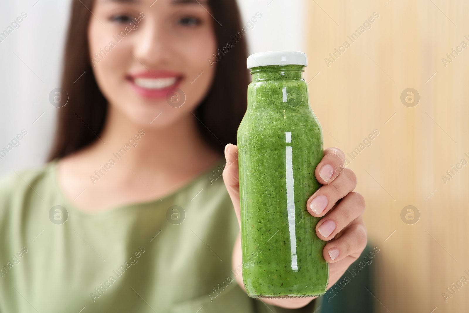 Photo of Woman with bottle of delicious smoothie, focus on hand