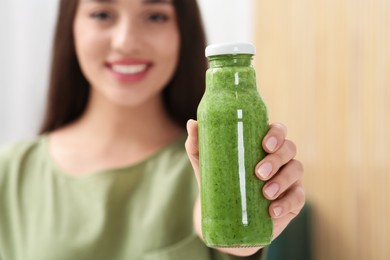 Photo of Woman with bottle of delicious smoothie, focus on hand