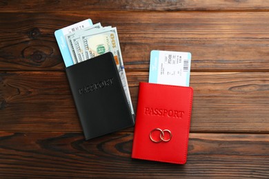 Photo of Honeymoon concept. Two golden rings, passports, money and tickets on wooden table, top view