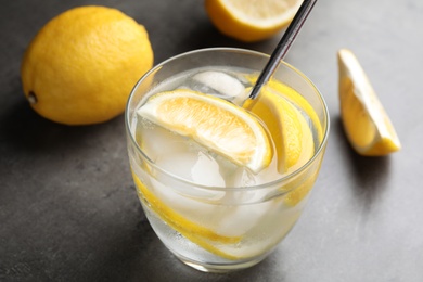 Photo of Soda water with lemon slices and ice cubes on grey table