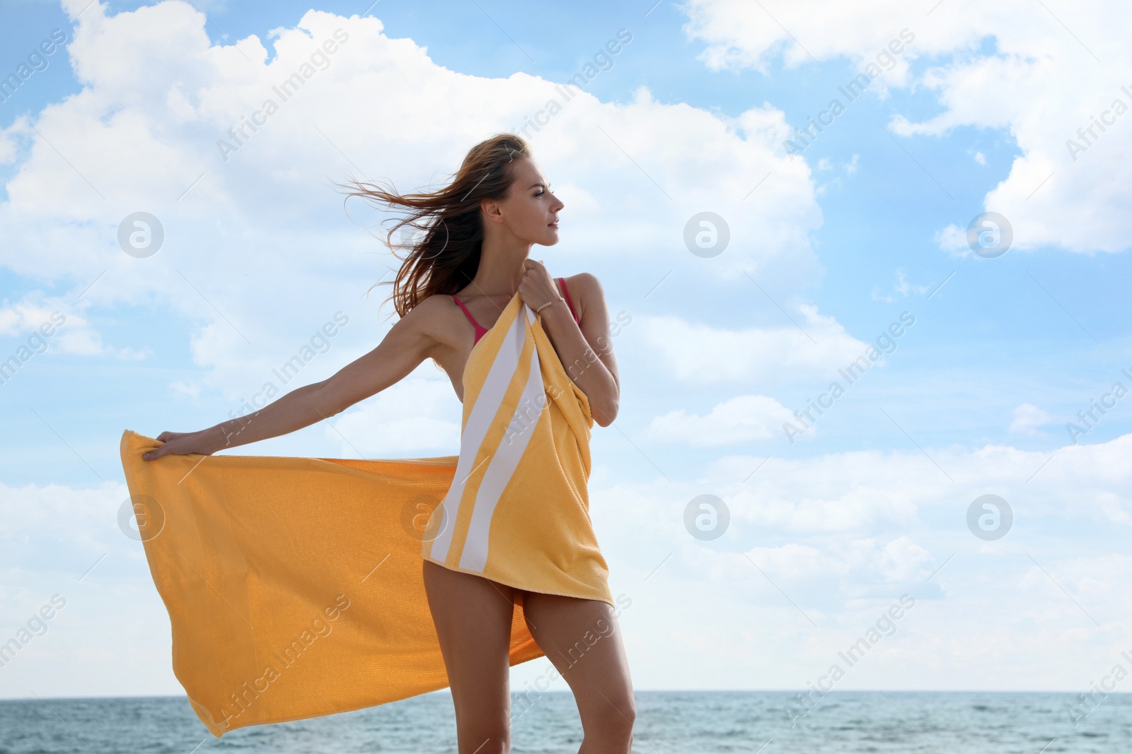 Photo of Beautiful woman with bright beach towel near sea