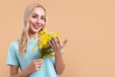 Happy young woman with beautiful bouquet on beige background. Space for text