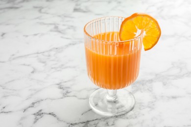 Delicious tangerine liqueur in glass on white marble table, closeup. Space for text