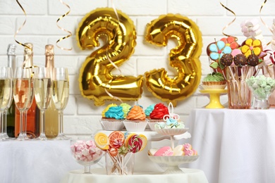Photo of Dessert table in room decorated with golden balloons for 23 year birthday party