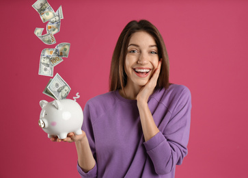 Image of Young woman with piggy bank on pink background