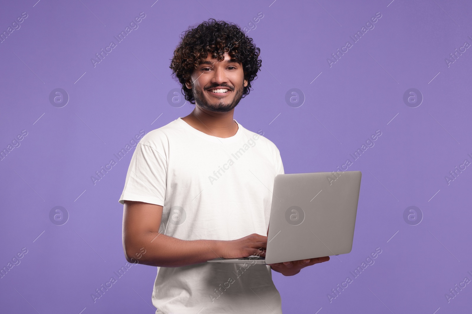 Photo of Smiling man with laptop on purple background