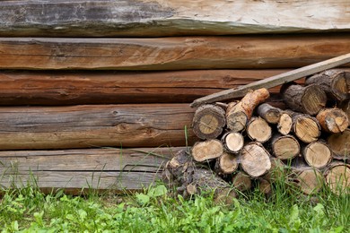 Pile of cut firewood near wooden wall on summer day, space for text