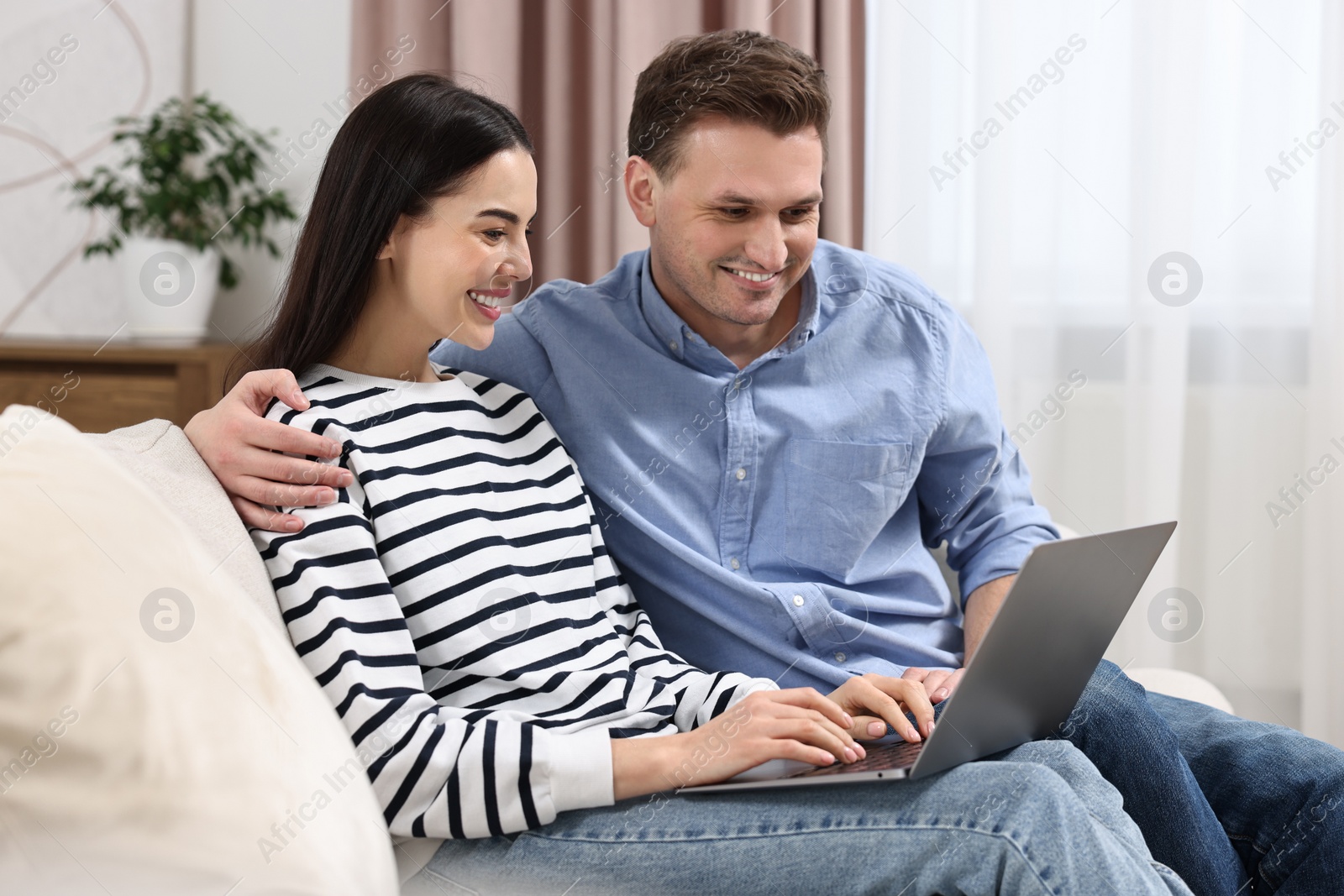 Photo of Happy couple using laptop together at home