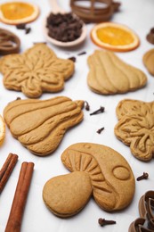 Different tasty cookies and spices on white table, closeup